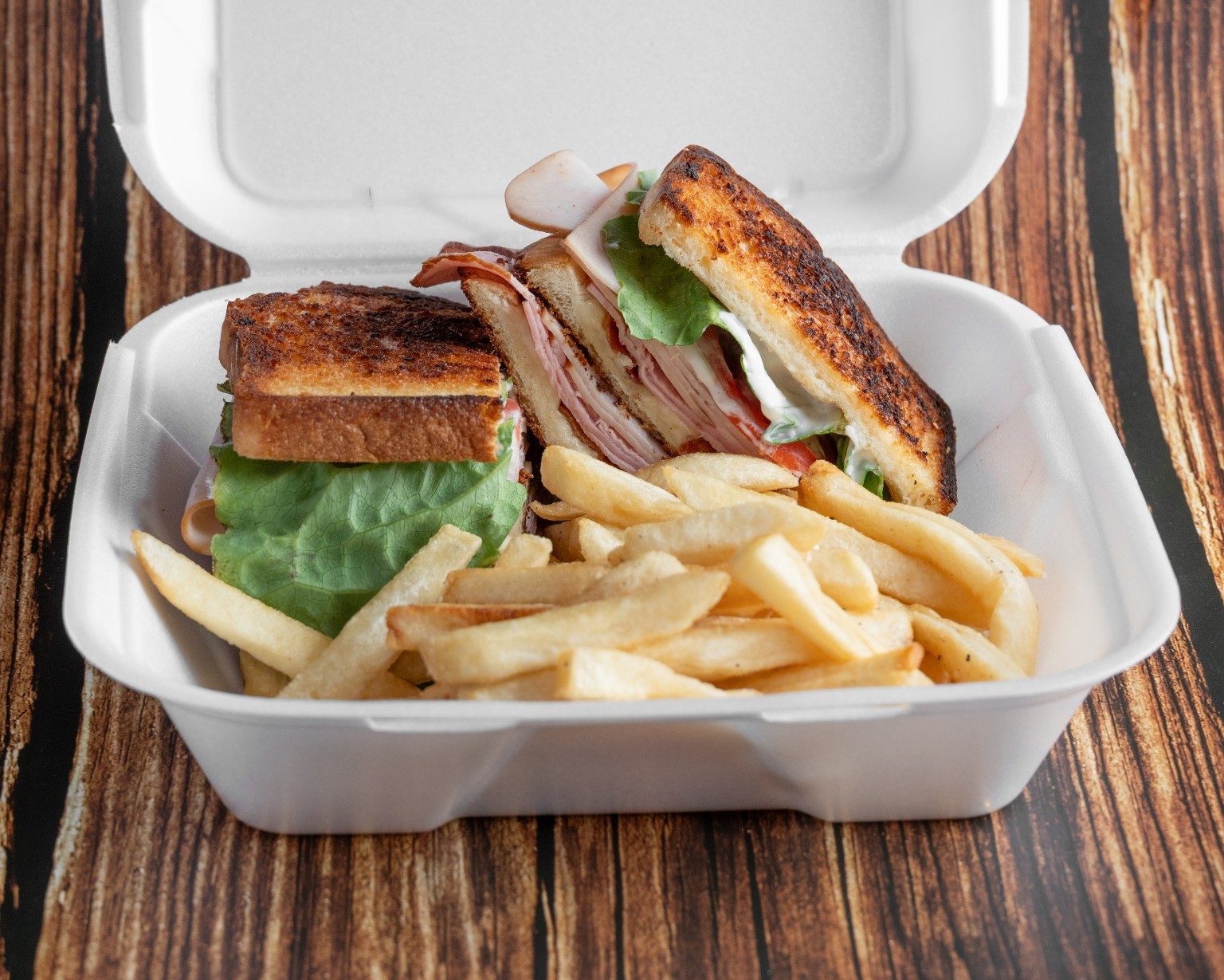 A stacked toasted club sandwich served with fries
