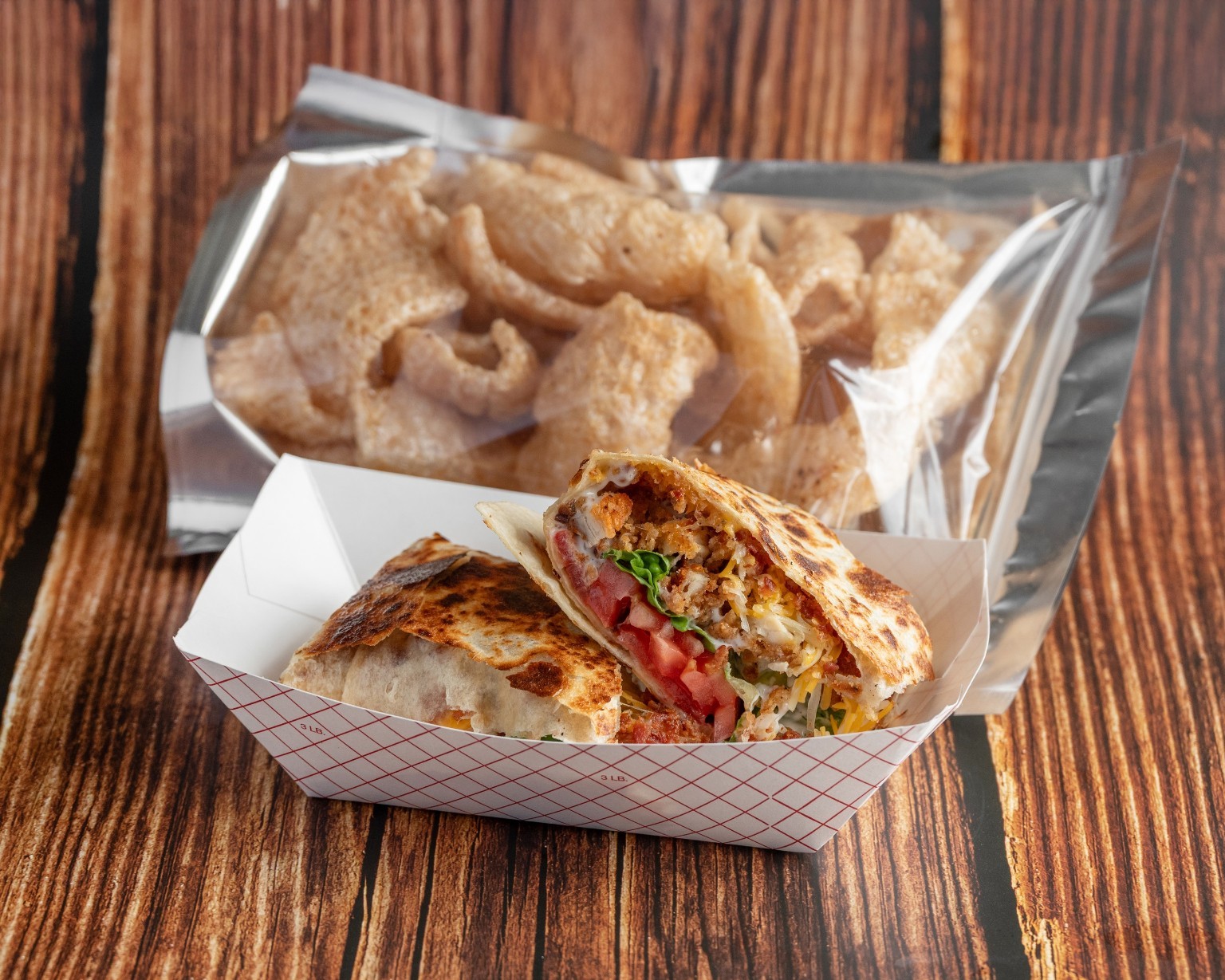 A toasted filled wrap beside crispy pork skins